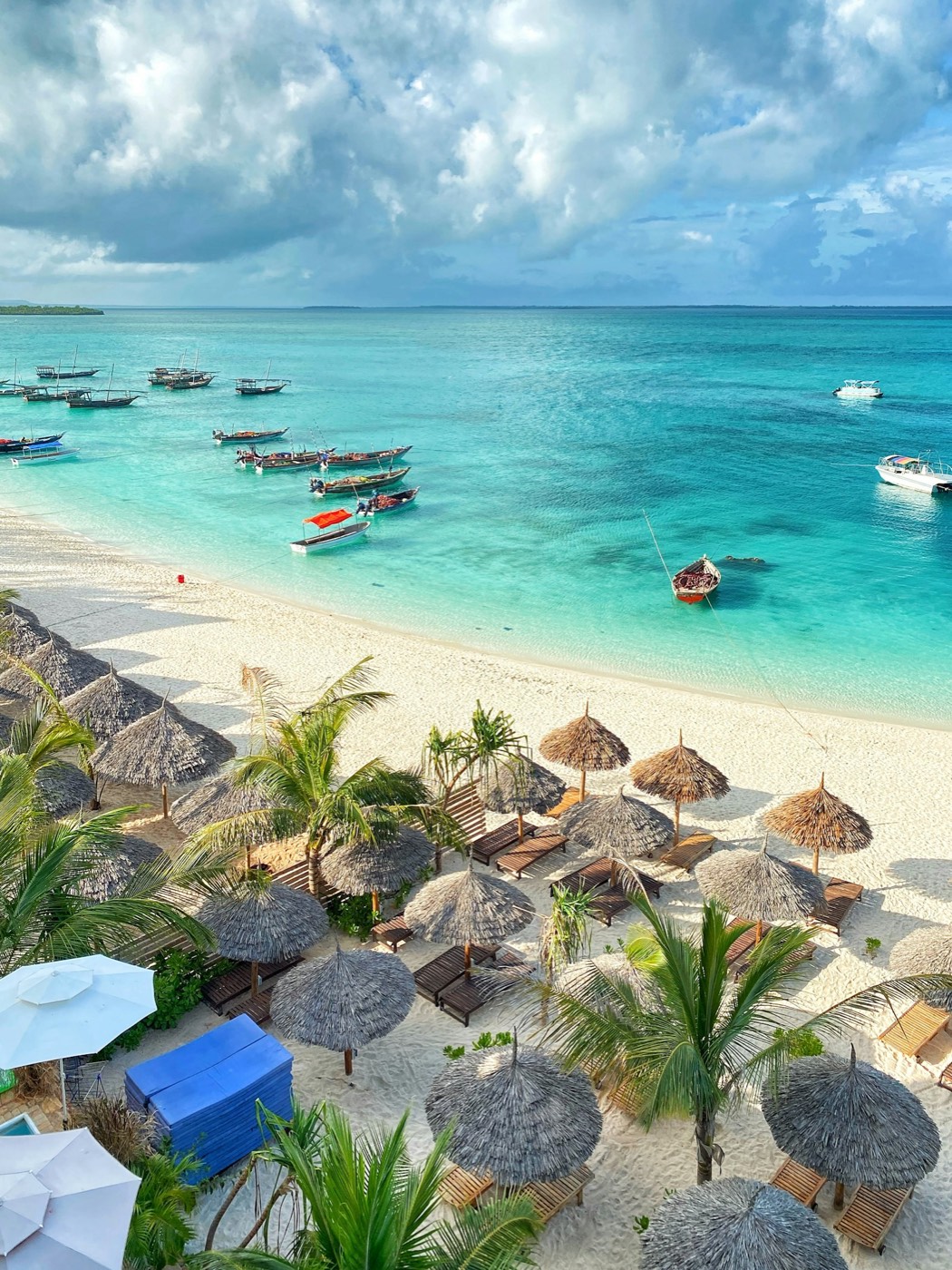 Wooden boats anchored in turquoise water off a Zanzibar beach
